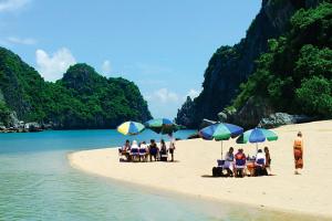 eine Gruppe von Menschen, die am Strand mit Sonnenschirmen sitzen in der Unterkunft Hanoi Amorita Boutique Hotel & Travel in Hanoi