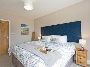 1 dormitorio con 1 cama grande y cabecero azul en The Cart Shed en Witton Gilbert