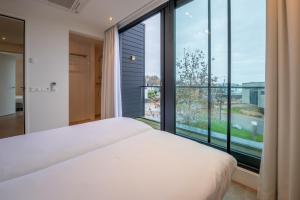 a bedroom with a bed and a large window at Harbour Villas Zeeland in Arnemuiden