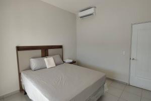 Schlafzimmer mit einem weißen Bett mit einem Kopfteil aus Holz in der Unterkunft Cómoda casa en Residencial San Andrés in San Miguel