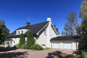 a white house with a black roof and a garage at Olsbacka Gård in Falun