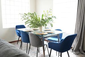 una mesa de comedor con sillas azules y un jarrón de flores en The Dahlia en Ciudad del Cabo