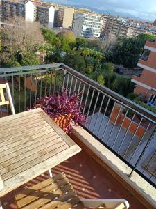 a balcony with a wooden bench and a table and flowers at Il Coriandolo 2 in Rome