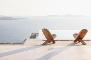 un paio di panche di legno sedute sul lato di un edificio di Birdhouse Private Luxury Suite ad Agios Ioannis