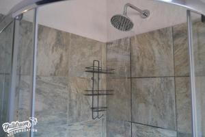 a shower in a bathroom with a stone wall at Clarky's Bucketlist in Dullstroom