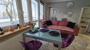 a living room with a table and purple chairs at Modlin Deluxe Suite in Nowy Dwór Mazowiecki