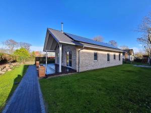 a brick house with a deck on a lawn at Ferienhaus "Achter de Schmeed" in Westfehmarn