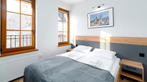 a bedroom with a bed and two windows at Wonder Home - Apartamenty Karkonosz blisko wyciągów narciarskich, szlaków i restauracji in Karpacz