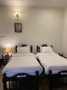 two beds sitting next to each other in a room at Dera Padlia - A Rural Experience Farm Stay 
