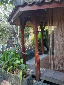 a wooden gazebo with a bench in a garden at Calmness Villa Syariah in Sekupang