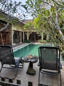 two chairs and a table next to a swimming pool at Calmness Villa Syariah in Sekupang