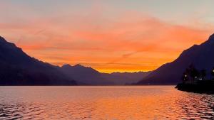 einen Sonnenuntergang über einem See mit Bergen im Hintergrund in der Unterkunft Romantic Lake & Mountain apartment Pure Swissness in Brienz