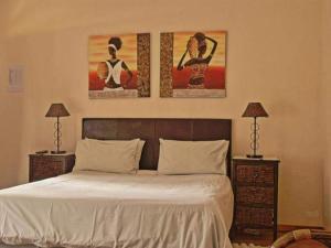 a bedroom with a bed with three paintings on the wall at Robs Place in Potchefstroom