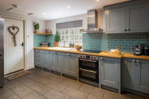 uma cozinha com armários cinzentos e um lavatório em Bridge End Cottage em Stainforth