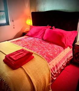 a bed with red sheets and red pillows on it at Orient House in Exeter