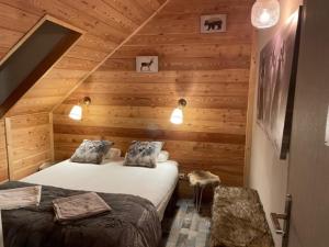 two beds in a room with wooden walls at Chez nous piste noire in Briançon