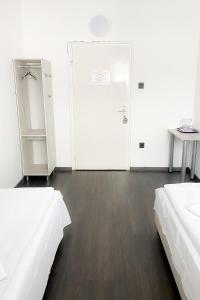 a white room with two beds and a door at Dominik Panzió in Budapest