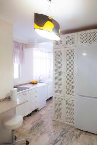 cocina con armarios blancos y nevera blanca en SJE - Shiny apartment close to the river en Sevilla