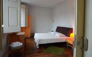 niewielka sypialnia z białym łóżkiem i drewnianą podłogą w obiekcie HI Guimaraes - Pousada de Juventude w mieście Guimarães