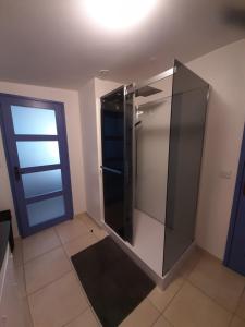 a bathroom with a glass shower with a blue door at ON LOGE A PIED ET A CHEVAL in Jonzac