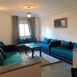 - un salon avec un canapé bleu et une table dans l'établissement Appart Hôtel Tanger Paname, à Tanger