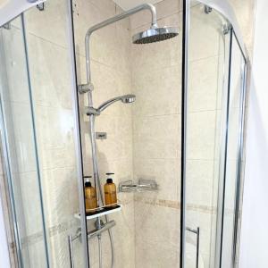 eine Dusche mit einer Glastür mit zwei Flaschen auf einem Regal in der Unterkunft Oxford Kidlington 6 Bed 5 mins to Oxford Parkway in Kidlington + 28 Fotos