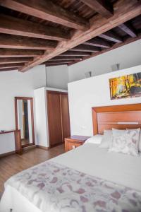 um quarto com uma grande cama branca e tectos em madeira em Hotel Gastronómico Gandainas em Riós