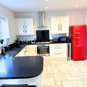 a kitchen with a red refrigerator and white cabinets at Oxford Kidlington 6 Bed 5 mins to Oxford Parkway in Kidlington