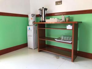 a kitchen with a shelf with a microwave and a refrigerator at SG Hotel in El Nido