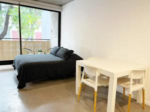 a bedroom with a bed and a table and a window at Mono Ambiente en Palermo Hollywood in Buenos Aires