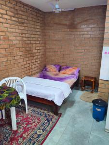 a bedroom with a bed and a brick wall at SJ Kololi Apartments in Sere Kunda