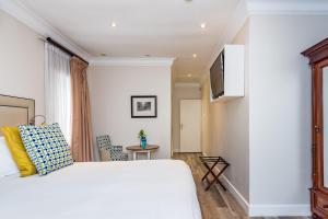 een slaapkamer met een wit bed en een televisie bij Clico Boutique Hotel in Johannesburg