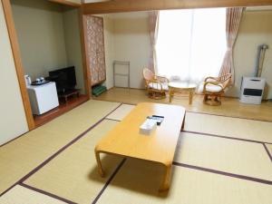 a living room with a coffee table and a room with a tv at Ryokan HANAEMI in Otaru