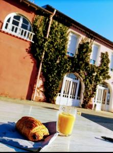 a glass of orange juice and a piece of bread on a table at Le Castel d'olmes in Laroque-dʼOlmes