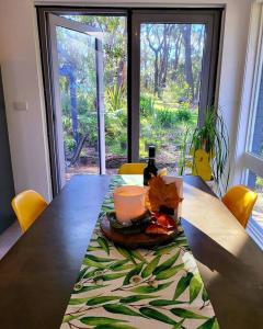 una mesa con una botella de vino y una vela en ella en The Yellow Koala - Vibrant Home in Medlow Bath, en Medlow Bath