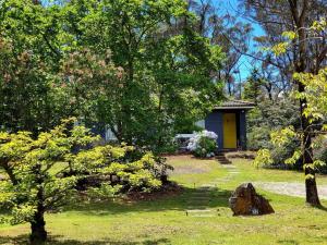 una pequeña casa con una puerta amarilla en un patio en The Yellow Koala - Vibrant Home in Medlow Bath, en Medlow Bath