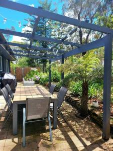 un patio con mesa y sillas bajo una pérgola azul en The Yellow Koala - Vibrant Home in Medlow Bath, en Medlow Bath