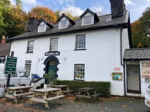 a white building with picnic tables in front of it at Lovely peaceful 2 bed cottage in Llandderfel