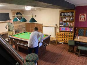 two men playing pool in a living room at Lovely peaceful 2 bed cottage in Llandderfel