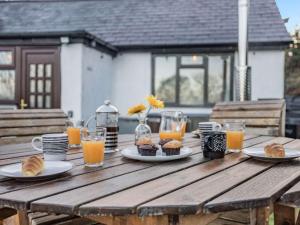 a wooden table with plates of food and orange juice at 2 bed in Denbigh 90461 in Caerwys