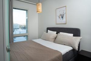 a bedroom with a bed with white sheets and a window at Holiday Apartment Aava 3 in Rovaniemi