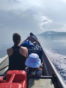 due persone e un bambino in una barca sull'acqua di Arborek Diving Homestay R4 a Besir