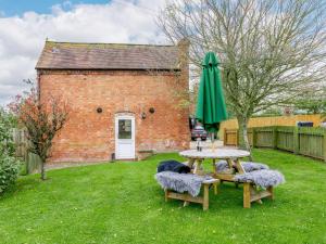 a picnic table and a green umbrella in a yard at 1 bed in Ledbury 90349 in Eldersfield