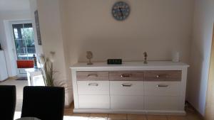 a white dresser in a room with a clock on the wall at Ferienwohnung - Unsere Wenke in Lemkendorf