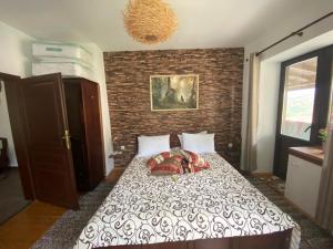 een slaapkamer met een bed met een bakstenen muur bij Каменната къща in Borovo