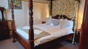 um quarto com uma cama de dossel com lençóis brancos em Ardbrecknish House em Dalmally