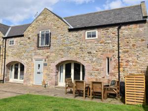 a stone house with a table and chairs in front of it at 3 Bed in Ellingham 90380 in Eglingham