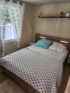 1 dormitorio con cama con almohada azul y ventana en Chez Monique et Marcel, en Parentis-en-Born