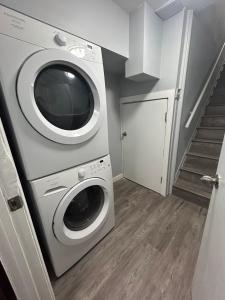 a laundry room with a washing machine and a staircase at Cute Highlandpark (Lower A Unit) in Calgary