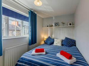 a bedroom with a blue and white bed with red pillows at 3 Bed in Bamburgh 90351 in Belford